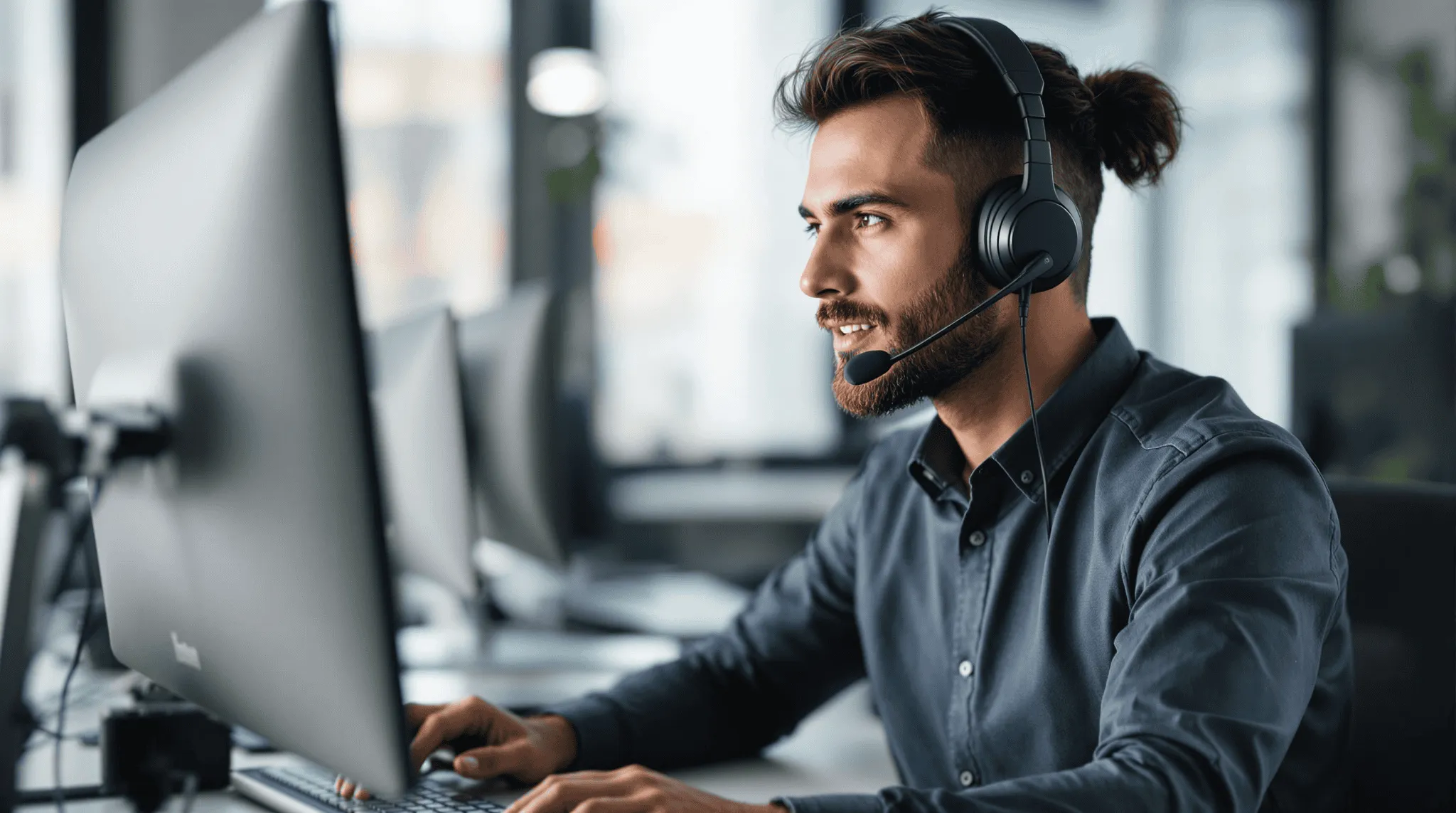 Säljare med headset arbetar vid en dator i ett modernt kontorslandskap